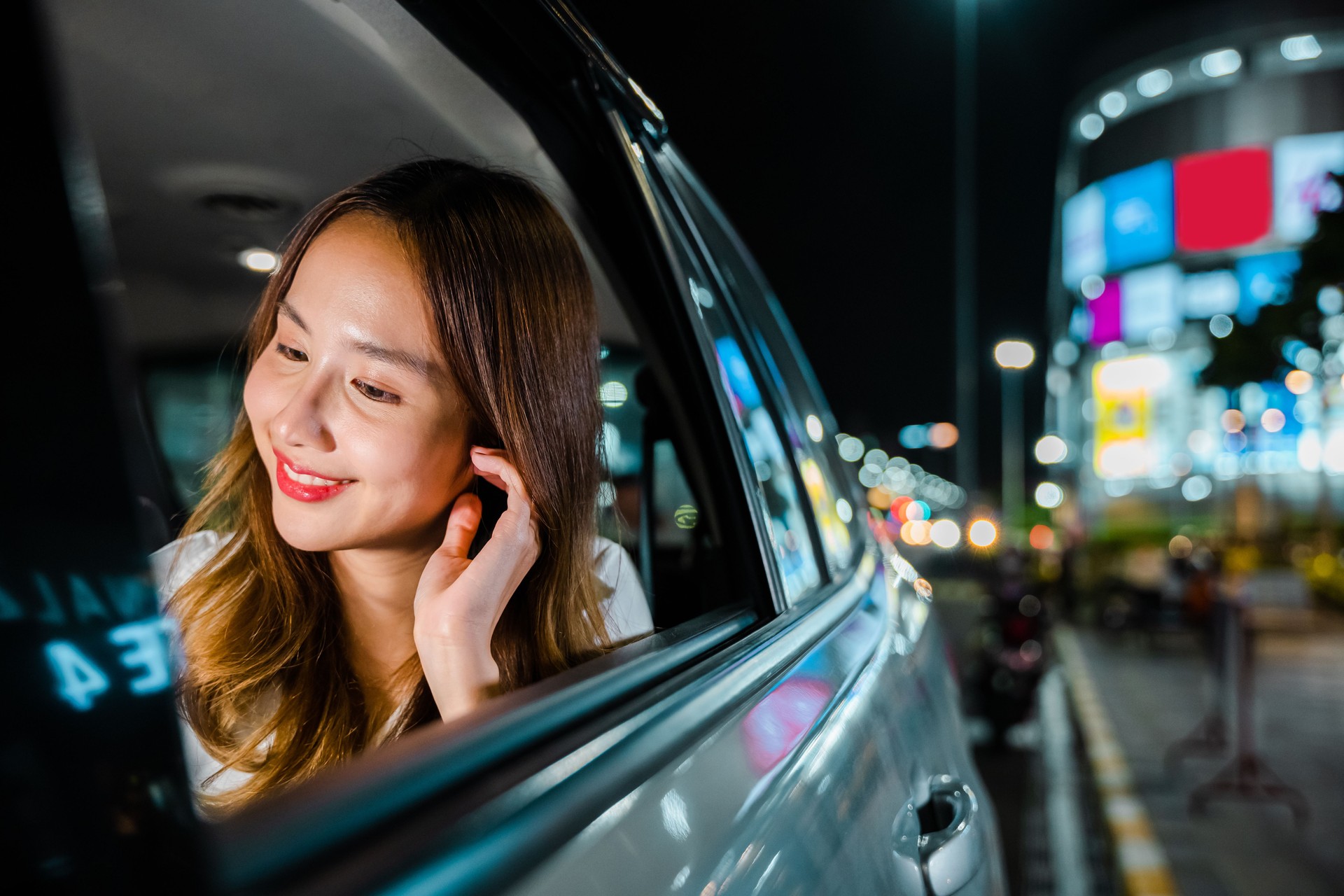 Asiatische Geschäftsfrau, die vom Büro in Taxi-Rücksitz mit Mobiltelefon auf der Straße pendelt